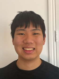 Smiling man with short black hair wearing a black shirt.