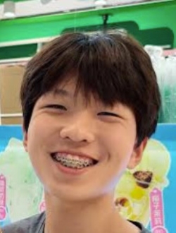 Man with short black hair smiling with braces and a colorful background.