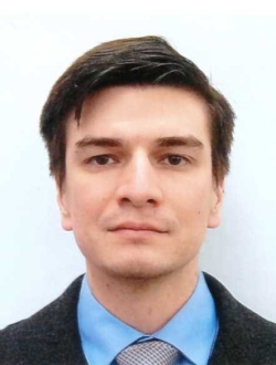 Man with short dark brown hair wearing a suit and tie.