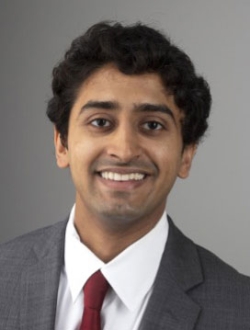 Smiling man with short curly black hair.