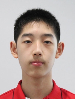 Young man with short black hair wearing a red polo shirt with a gray background.