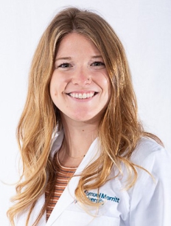 Smiling woman with long wavy blonde hairs wearing a white lab coat.