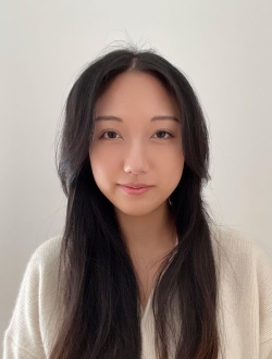 Woman with long black hair wearing a white sweater.