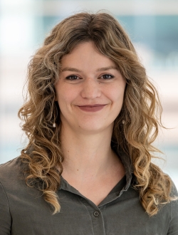 Woman with long wavy blonde hair wearing a green collard shirt.