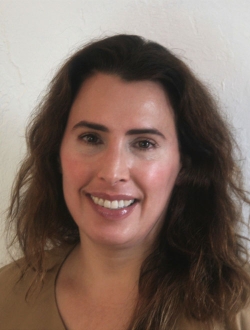 Smiling woman with long curly brown hair.