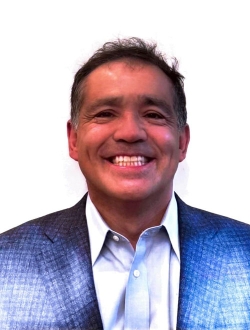Smiling man with short dark hair wearing a blue suit jacket.