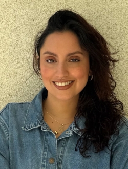 Smiling woman with long wavy black hair wearing a blue shirt.