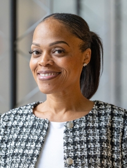 Smiling woman with dark hair pulled back wearing a black and white checked jacket and white top.