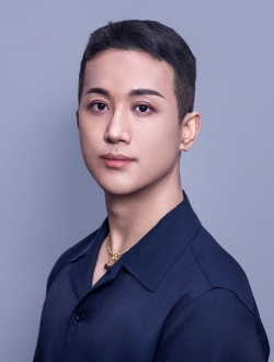 Person with short dark hair wearing a blue shirt.