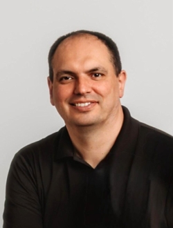 Smiling man with short dark hair wearing a black shirt.
