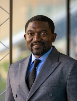 A man with short dark hair wearing a dark blue suit and tie.