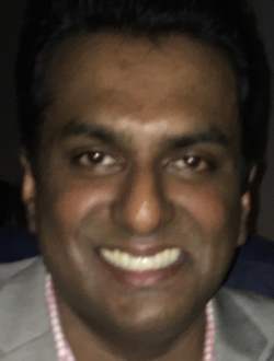 Smiling man wearing a gray suit jacket.