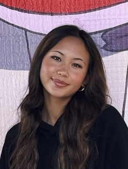 Woman with long wavy dark brown hair wearing a black sweater.