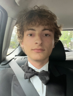 Man with short curly brown hair wearing a tuxedo.