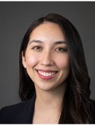 Smiling woman with shoulder length black hair wearing a black jacket.