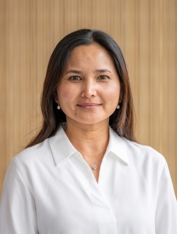 Person with long dark brown hair wearing a white shirt.