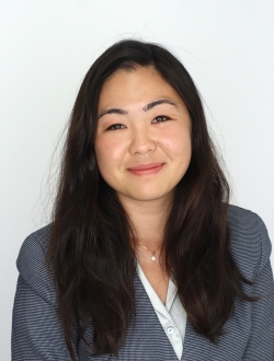 Woman with long black hair wearing a dark gray jacket.