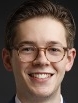 Smiling man with short brown hair wearing glasses.