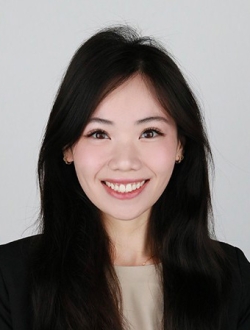 Smiling person with long straight black hair wearing a black jacket and beige top.