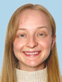 Smiling person with long straight blonde hair wearing a light beige turtleneck sweater.