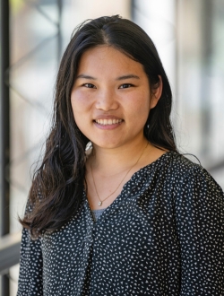 Woman with long dark brown hair wearing a black and white patterned shirt.