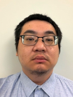Person with short black hair wearing glasses and a blue shirt.