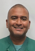 man in green scrubs smiling.