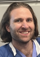 a man in scrubs smiling at the camera.