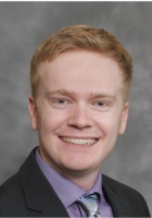 Smiling man with red hair wearing a suit and tie.