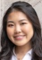 Smiling woman with long dark hair wearing a jacket and shirt.