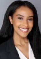 Smiling woman with long black hair wearing a dark jacket over a white top.