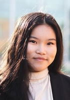 Woman with long dark brown hair wearing a dark brown jacket.