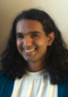 Smiling woman with long curly dark hair.