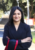 Woman with long black hair wearing a black jacket with her arms crossed.