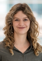 Woman with long wavy blonde hair wearing a green collard shirt.