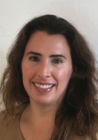 Smiling woman with long curly brown hair.
