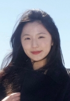 A woman with long black hair standing outside wearing black.