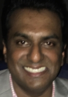 Smiling man wearing a gray suit jacket.