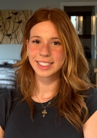 Smiling woman with long wavy light brown hair wearing a black t-shirt.