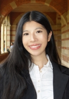 Smiling person with long black hair wearing a black jacket over a white shirt.