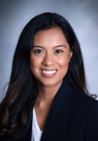 Smiling person with long black hair wearing a black jacket over a white shirt.