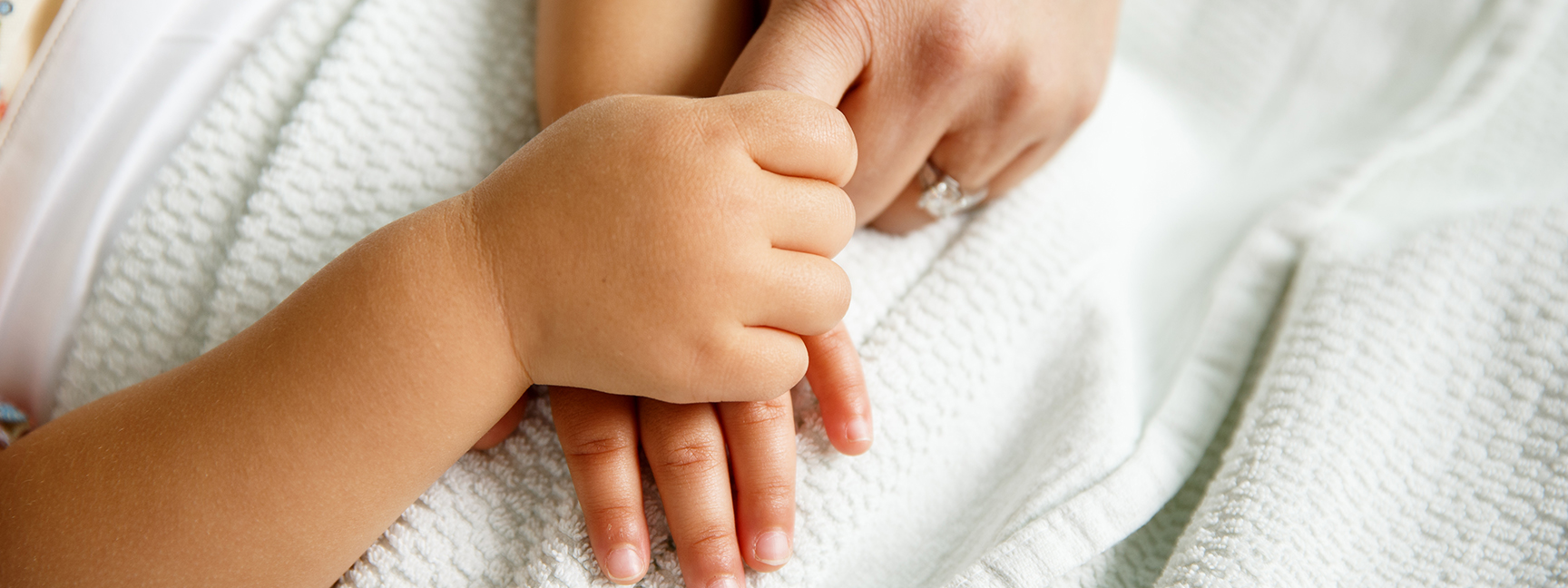 Child's hand gripping parent's finger